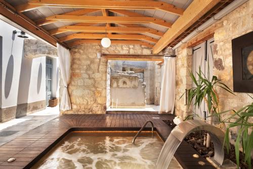 bañera de hidromasaje cubierta en una habitación con pared de piedra en Nars Ilica Hotel Beach Adults Only 12Plus, en Cesme