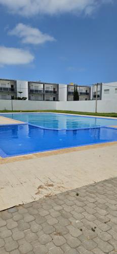 a swimming pool with blue water in front of a building at Résidence balnéaire avec piscine proche de la mer in Dar Hamida
