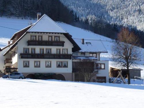 un gran edificio blanco con nieve en el suelo en Schiebenrothenhof en Simonswald