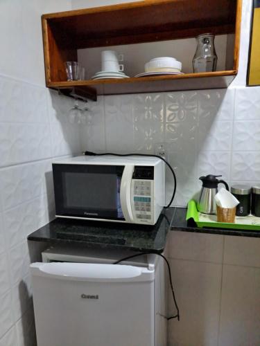 a microwave sitting on top of a refrigerator in a kitchen at Recanto das Flores Lofts - Ilha Grande Rj in Abraão