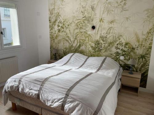 - une chambre avec un lit et un mur orné de plantes dans l'établissement Appartement moderne Proche mer, Le Pouldu, à Clohars-Carnoët