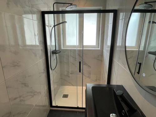 une douche avec une porte vitrée dans une salle de bain dans l'établissement Appartement moderne Proche mer, Le Pouldu, à Clohars-Carnoët