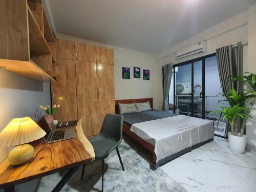 een slaapkamer met een bed en een bureau met een laptop bij 12A/89 Phạm Văn Đồng, Hà Nội in Hanoi