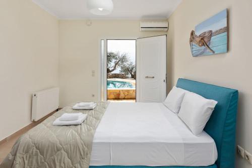 a bedroom with a white bed and a blue chair at Ionian Blue in Perama