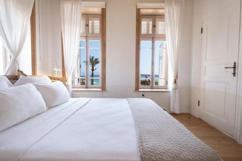 Schlafzimmer mit einem großen weißen Bett und Fenstern in der Unterkunft Nars Ilica Hotel Beach Adults Only 12Plus in Cesme