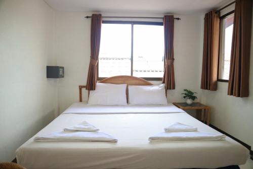 a bedroom with a large white bed with a window at Sunshine Guest House in Hua Hin