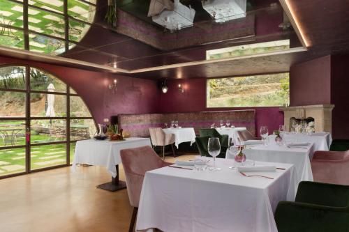 un restaurante con mesas y sillas blancas y ventanas en Can Font de Muntanya Turisme Rural, en Cruïlles