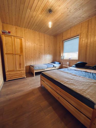a bedroom with two beds in a wooden room at Zielona Dolina Sarbinowo in Sarbinowo