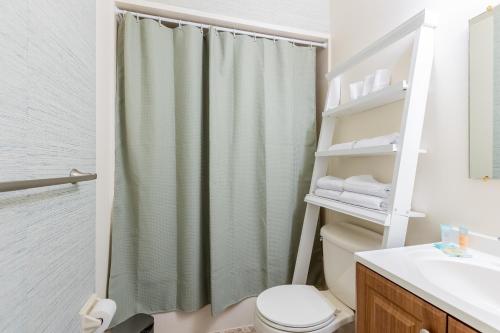Baño con cortina de ducha junto a un aseo en Cozy 2BR condo w/ valley views, en Vernon Township