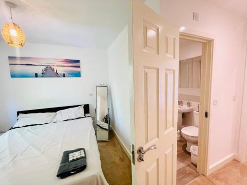 a white bedroom with a bed and a toilet at Chattel Bedford in Bedford