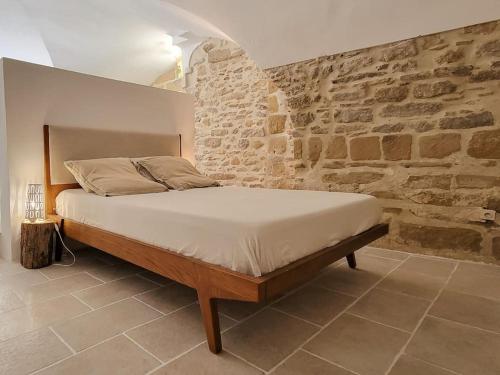 un lit dans une chambre avec un mur en pierre dans l'établissement Studio Spacieux de Caractère, à Montaren-et-Saint-Médiers