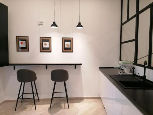 una cucina con due sgabelli, bancone e lavandino di I Canti Comfort Rooms a Palermo