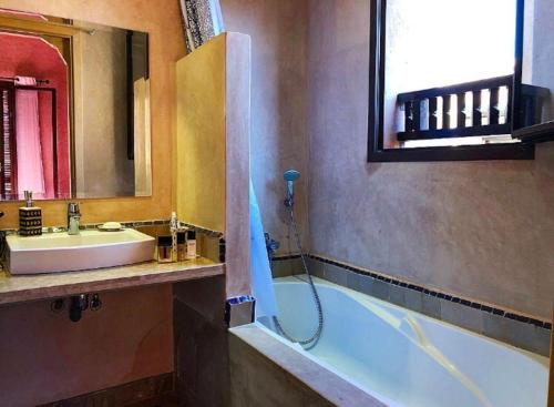 een badkamer met een wastafel en een bad met een douche bij Appartement avec vue sur l'Atlas et piscine in Marrakesh