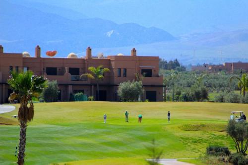 a group of people playing golf in front of a building at Appartement avec vue sur l'Atlas et piscine in Marrakech