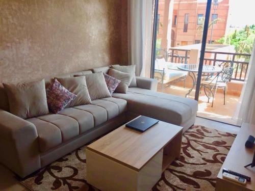 a living room with a couch and a table at Appartement avec vue sur l'Atlas et piscine in Marrakech