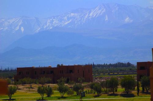 a red building with a mountain in the background at Appartement avec vue sur l'Atlas et piscine in Marrakech