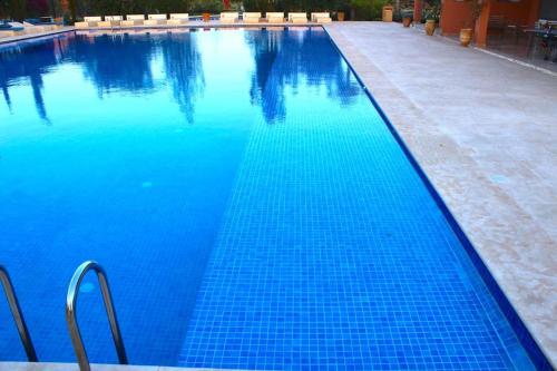 a large blue swimming pool with blue water at Appartement avec vue sur l'Atlas et piscine in Marrakech