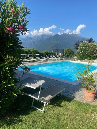 einen Pool mit Liegestühlen und Bergen im Hintergrund in der Unterkunft Casa Camilla in Colico