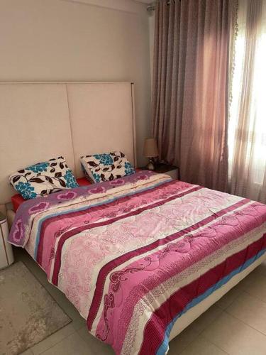 1 dormitorio con 1 cama con manta rosa y almohadas en superbe appartement S1, en Nabeul