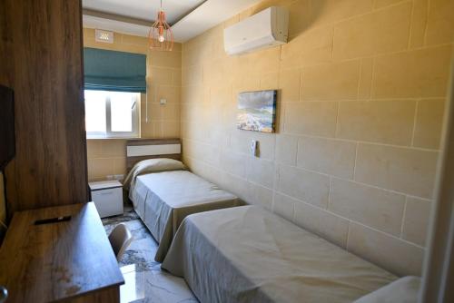 a small room with two beds and a window at Azure W B&B in San Lawrenz