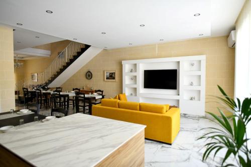 a living room with a yellow couch and a dining room at Azure W B&B in San Lawrenz