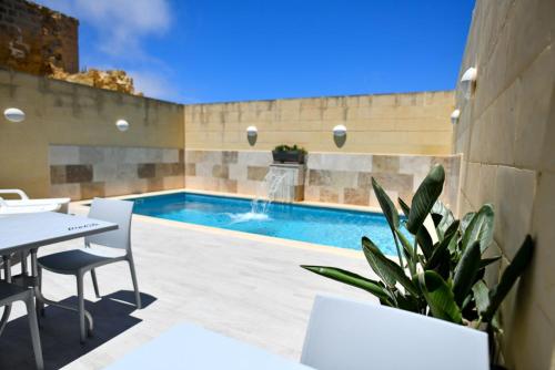 a patio with a pool and a table and chairs at Azure W B&B in San Lawrenz