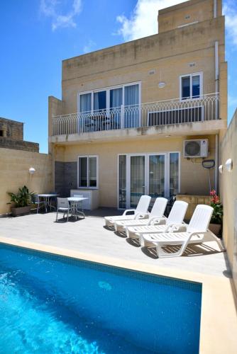 a villa with a swimming pool in front of a house at Azure W B&B in San Lawrenz