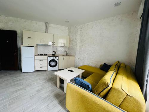 a living room with a yellow couch and a kitchen at Apartments NITA in Batumi