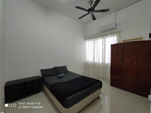 Schlafzimmer mit einem Bett und einem Deckenventilator in der Unterkunft Pool Smart Tv Wifi 3 aircond room Jitra Kolej Height Utara in Jitra