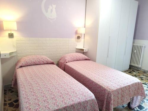two beds in a small room with pink covers at Appartamento Cervi - Casa in Affitto per Vacanze in Nichelino