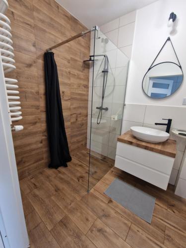 La salle de bains est pourvue d'une douche et d'un lavabo. dans l'établissement 60 - Apartamenty Siedlce - Nowy apartament w centrum przy ul 3 Maja 51a, à Siedlce