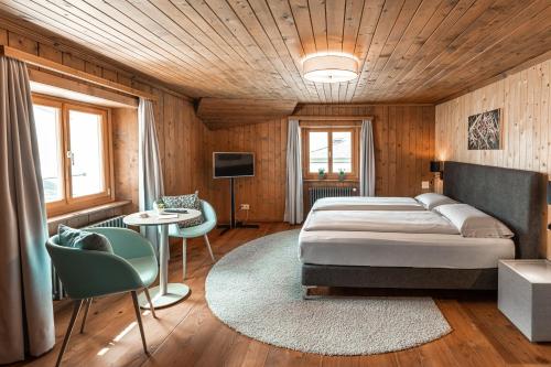1 dormitorio con 1 cama, mesa y sillas en Historic Hotel Albrici en Poschiavo