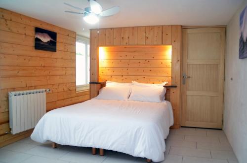 1 dormitorio con cama blanca y pared de madera en Maison d'hôtes MIRADOUR, en Tarnos