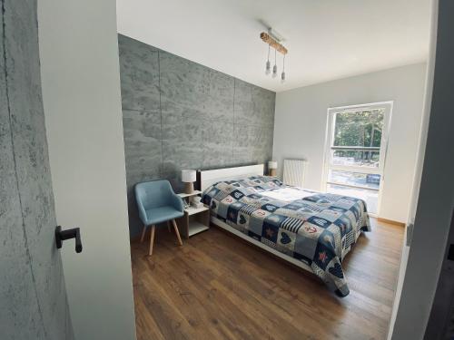 a bedroom with a bed and a chair and a window at Apartament Amilado in Pogorzelica