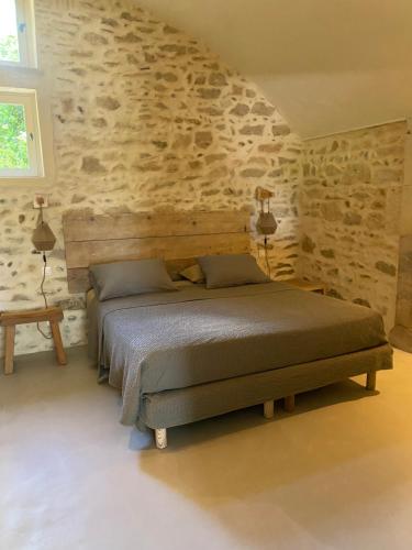 une chambre avec un lit et un mur en pierre dans l'établissement Appartement Éden - campagne avec piscine commune - Eyragues, à Eyragues