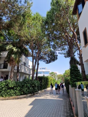 a group of people walking down a sidewalk with trees at Villa Pearl Adriatic Coast 2 in Golem