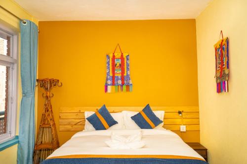 a bedroom with a bed with a yellow wall at Kwabahal Boutique Hostel in Kathmandu