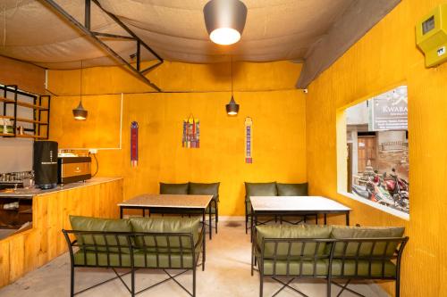 a restaurant with yellow walls and tables and chairs at Kwabahal Boutique Hostel in Kathmandu