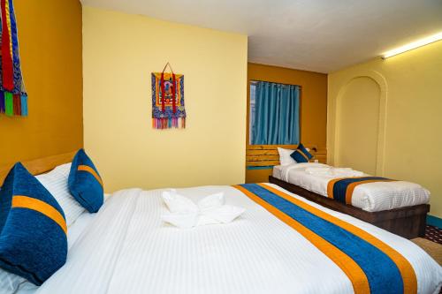 two beds in a room with yellow walls at Kwabahal Boutique Hostel in Kathmandu