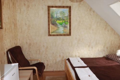 Zimmer mit einem Bett und einem Stuhl sowie einem Wandgemälde in der Unterkunft Arany Dió Fogadó in Eger