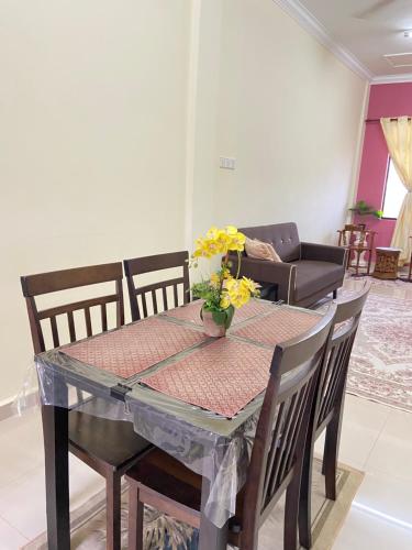 a dining room table with a vase of flowers on it at MNOOR HOMESTAY in Marang