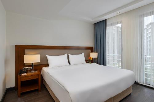 a bedroom with a large white bed and windows at Miracle Istanbul Asia Airport Hotel & Spa in Istanbul