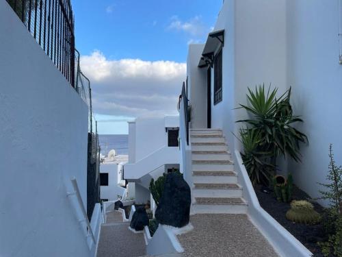 a staircase leading down to a white building with the ocean at The White Dragos with Ocean view in Tías