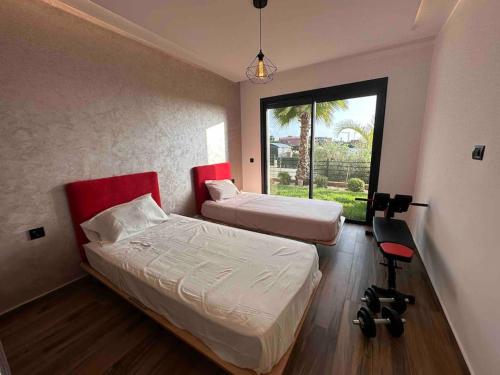 1 dormitorio con 2 camas, silla y ventana en SuperHost Modern Condo 5 mins to the beach!, en Dar Bouazza