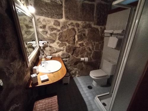 Baño de piedra con lavabo y aseo en Apartamentos Rias Baixas, en Moaña