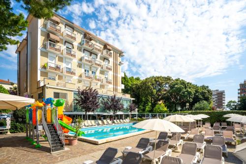 リミニにあるLotus Hotel ALL INCLUSIVE & SPIAGGIAのスイミングプールと椅子のあるホテル