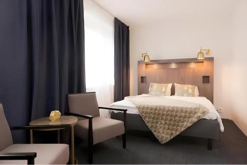 a bedroom with a large bed and a chair at Communia Hotel Residence in Stockholm
