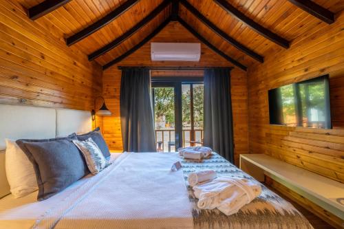 a bedroom with a bed with wooden walls and windows at Dolce Vita Luxury Bungalows in Bodrum City