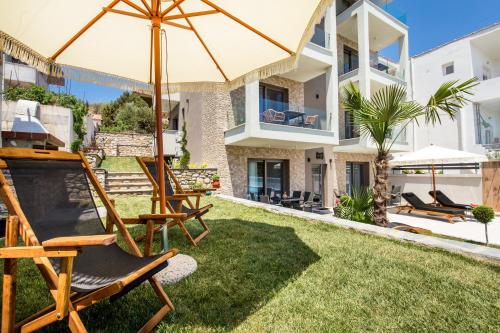 a yard with chairs and an umbrella and a house at Aigli Skala Maries Deluxe in Skala Marion