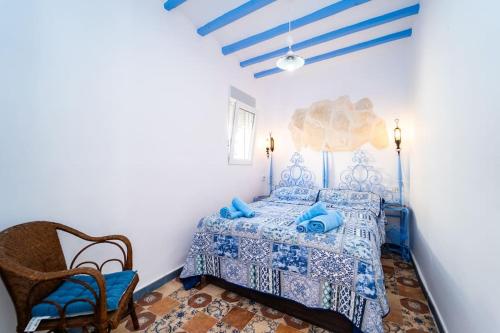 een slaapkamer met een blauw bed en een stoel bij Alhambra Dreams 1958 in Villajoyosa